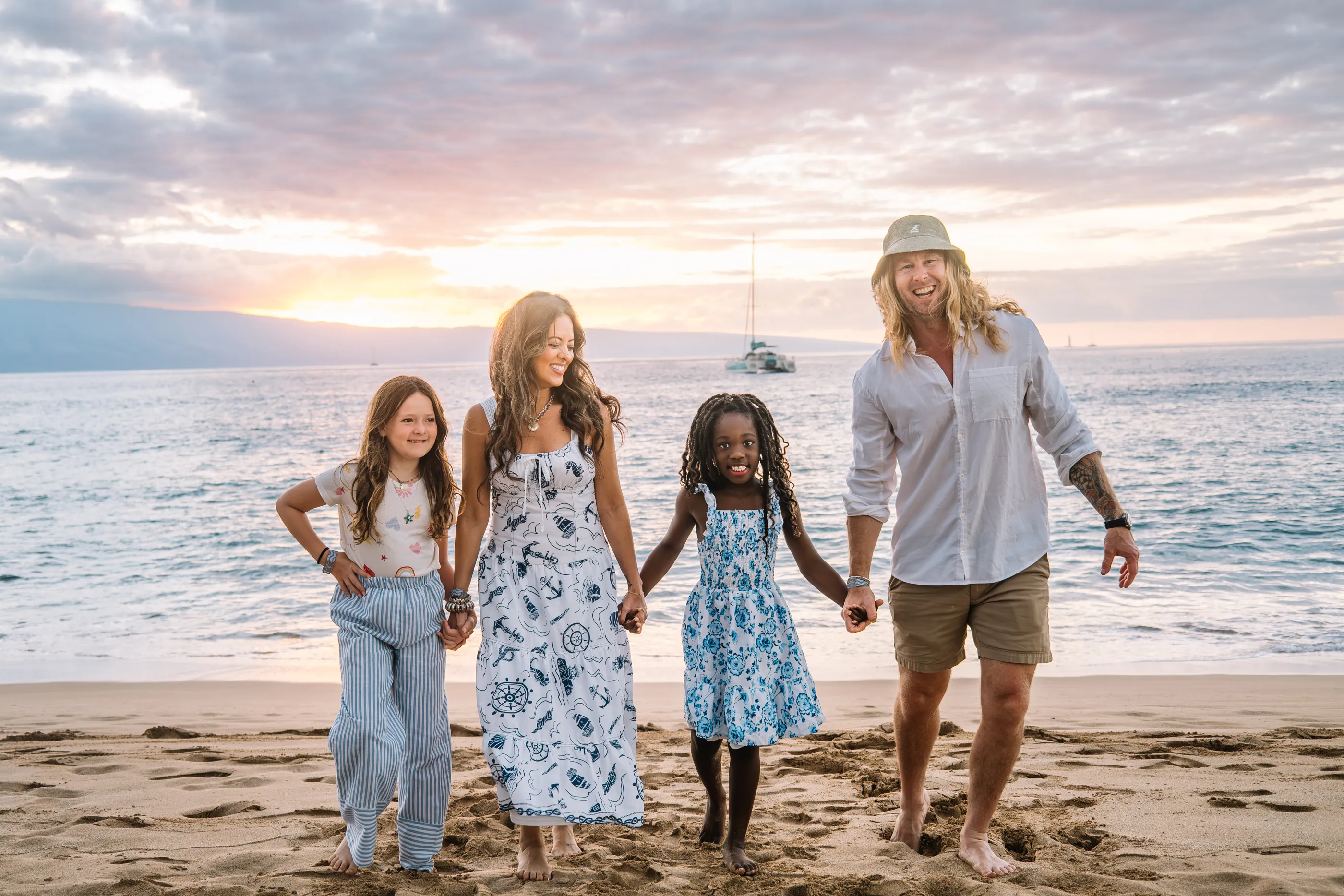 Jamey Ice walking with his wife Melissa and their two daughters on a beach at sunset.