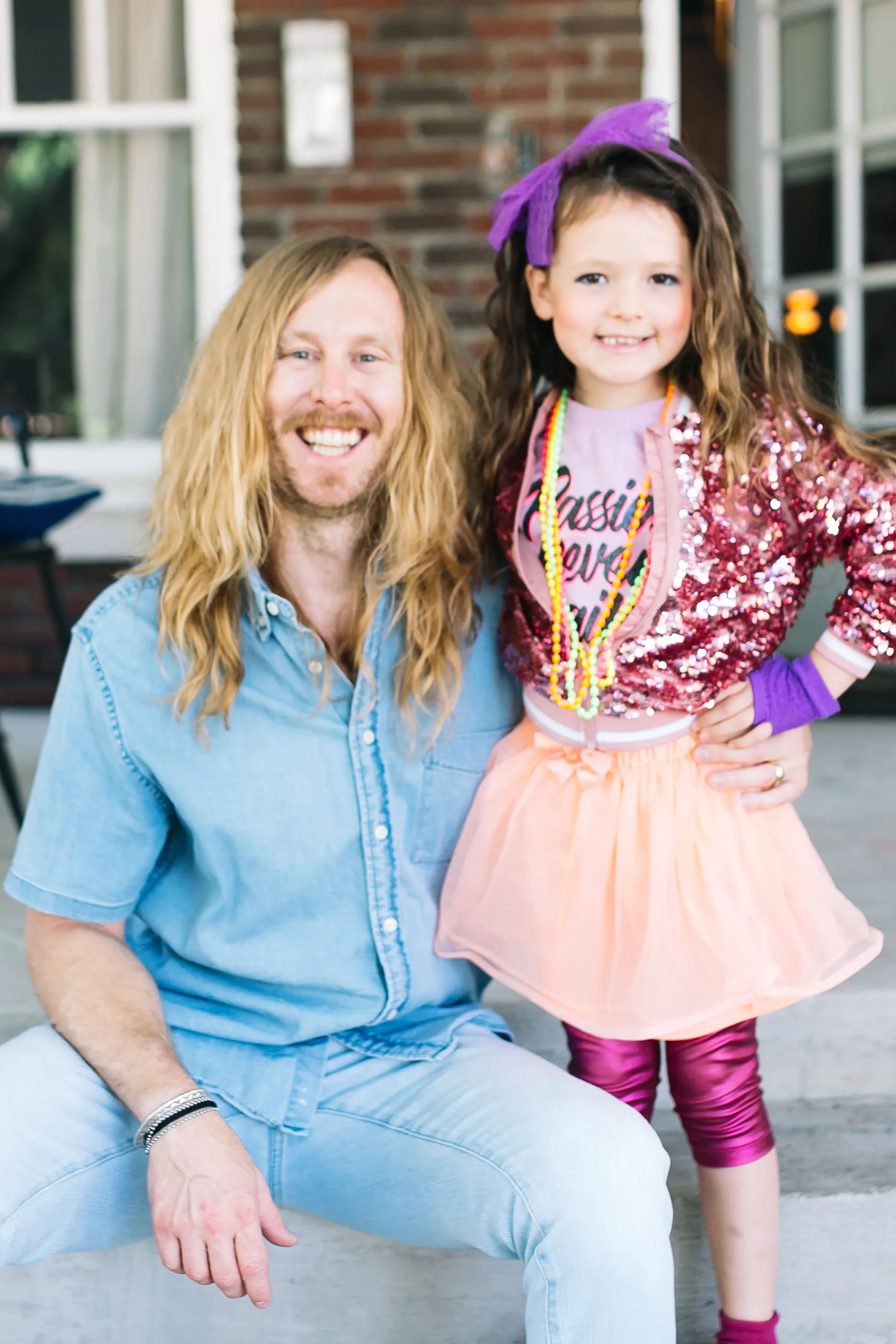 Jamey on porch steps with his daughter in purple bow.